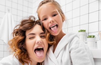 Laughing mom and daughter showing their tongues
